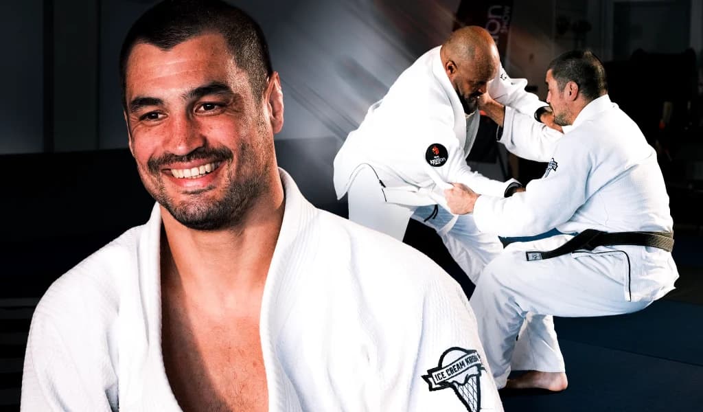 Kron Gracie smiling in a white gi with his Ice Cream Kron patch, with Kron Gracie and Selema Masekela grappling in the background.