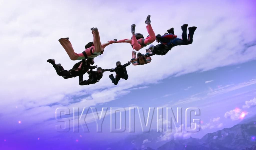 Group of skydivers holding formation midair above cloud-covered mountains.