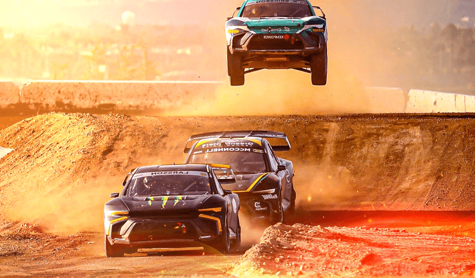 Nitrocross rally three cars rally race through a dusty trail with one catching some air