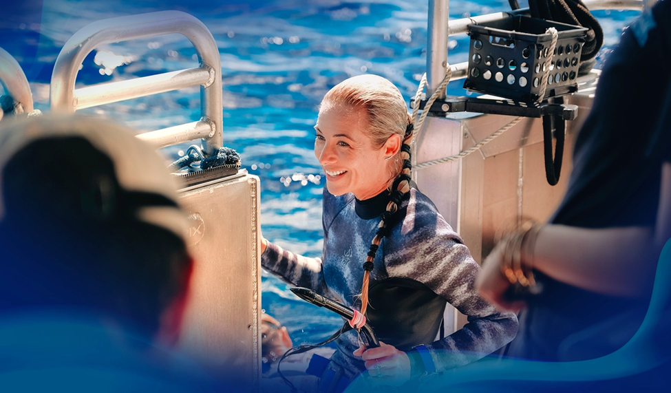 Ocean Ramsey smiling while preparing to dive from a boat, surrounded by the Team Ignition crew and blue ocean waters